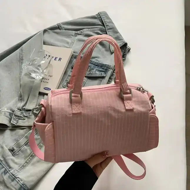 Pink textured duffel bag with zipper details and adjustable shoulder strap.